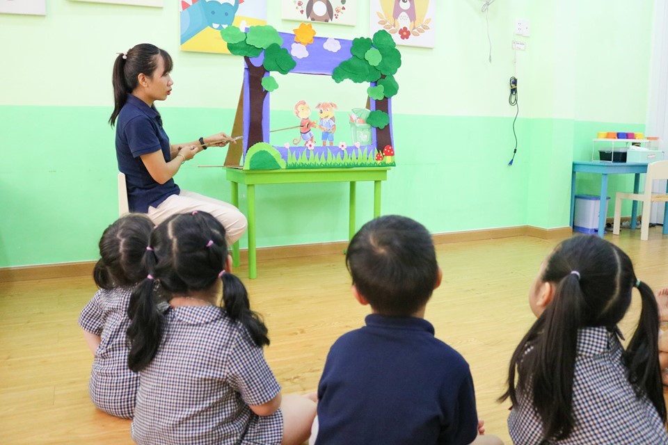 Cô Nghĩa kể chuyện qua sách, rồi cho xem phim hoạt hình về Khỉ con ăn chuối lần nữa để ghi nhớ
