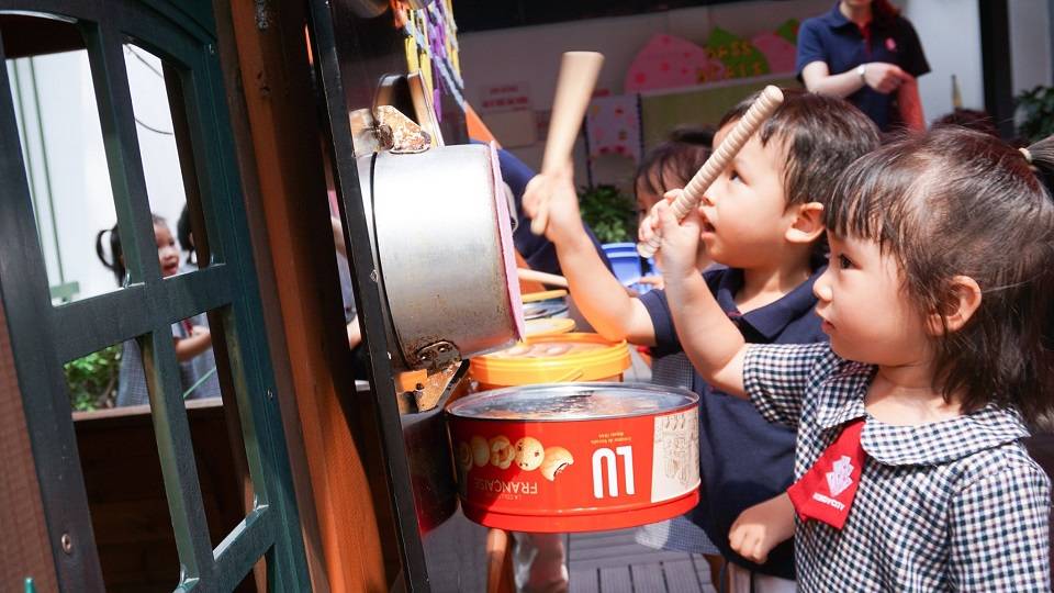 Trẻ đang mải mê biểu diễn nhạc cụ trên nền nhạc có lời trên sân khấu được các cô chuẩn bị sẵn