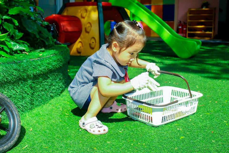 Bé chủ động nhặt rác giúp khoảng sân được sạch sẽ
